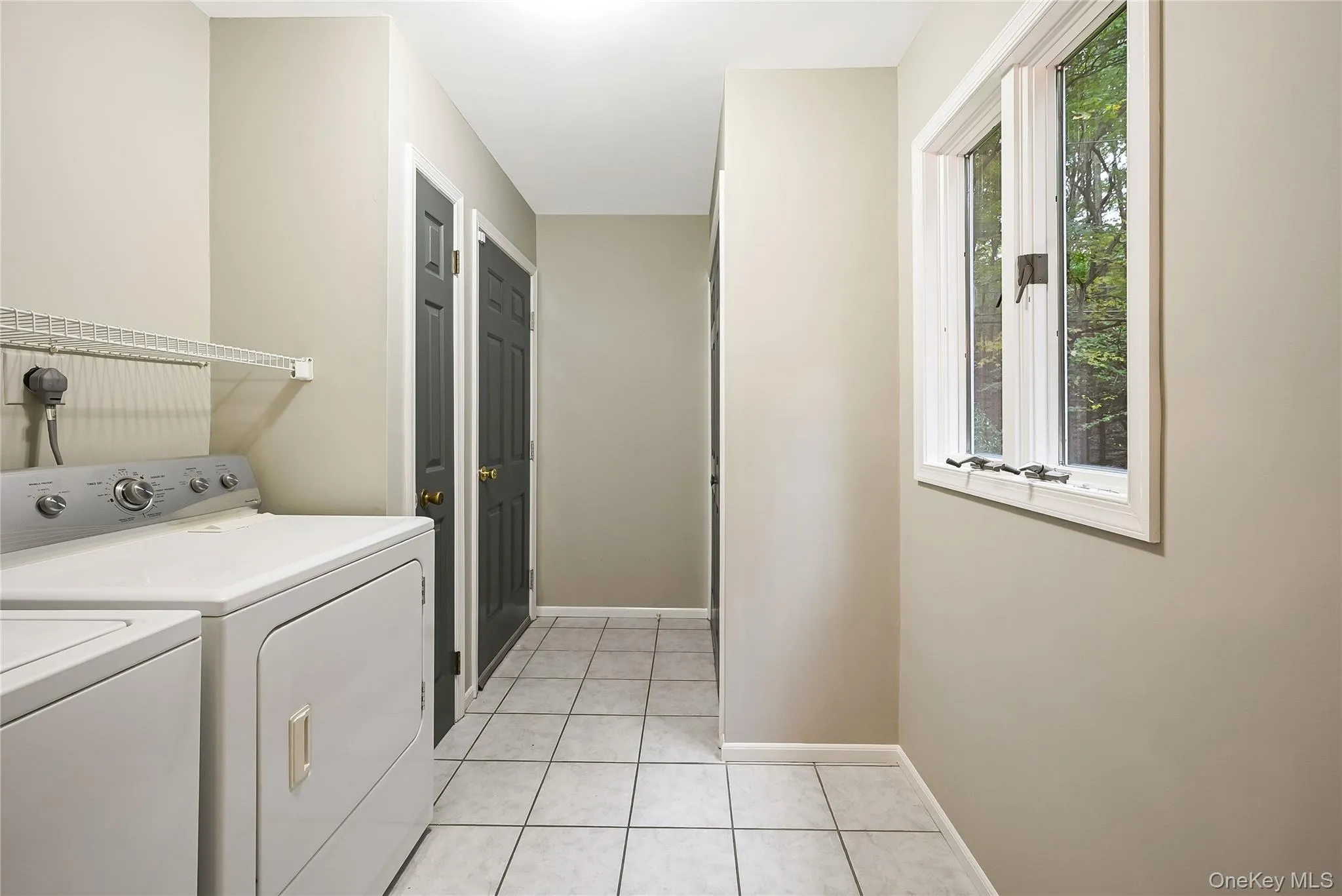 Laundry area with light tile patterned floors and washer and clothes dryer Laundry area with light tile patterned floors and washer and clothes dryer