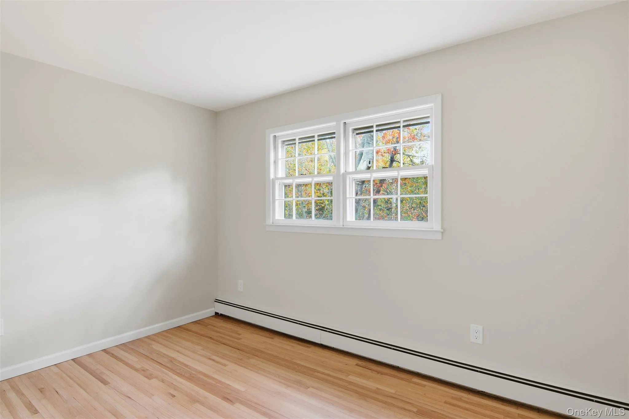 Empty room featuring baseboard heating and light wood-type flooring Empty room featuring baseboard heating and light wood-type flooring