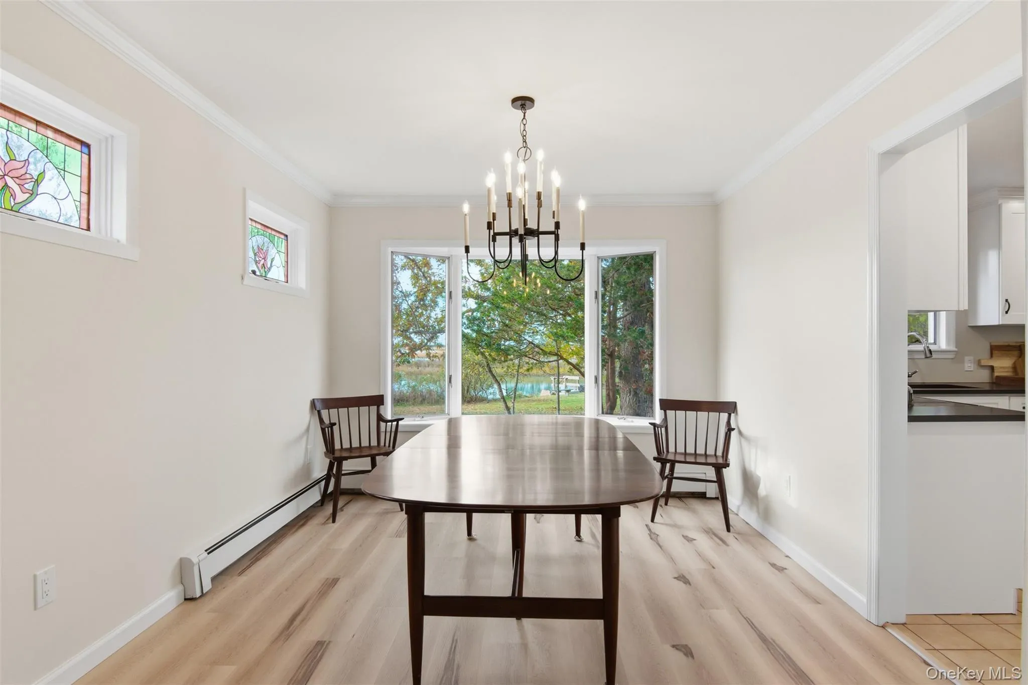 Dining area featuring a baseboard heating unit, light wood-style floors, ornamental molding, and a chandelier Dining area featuring a baseboard heating unit, light wood-style floors, ornamental molding, and a chandelier