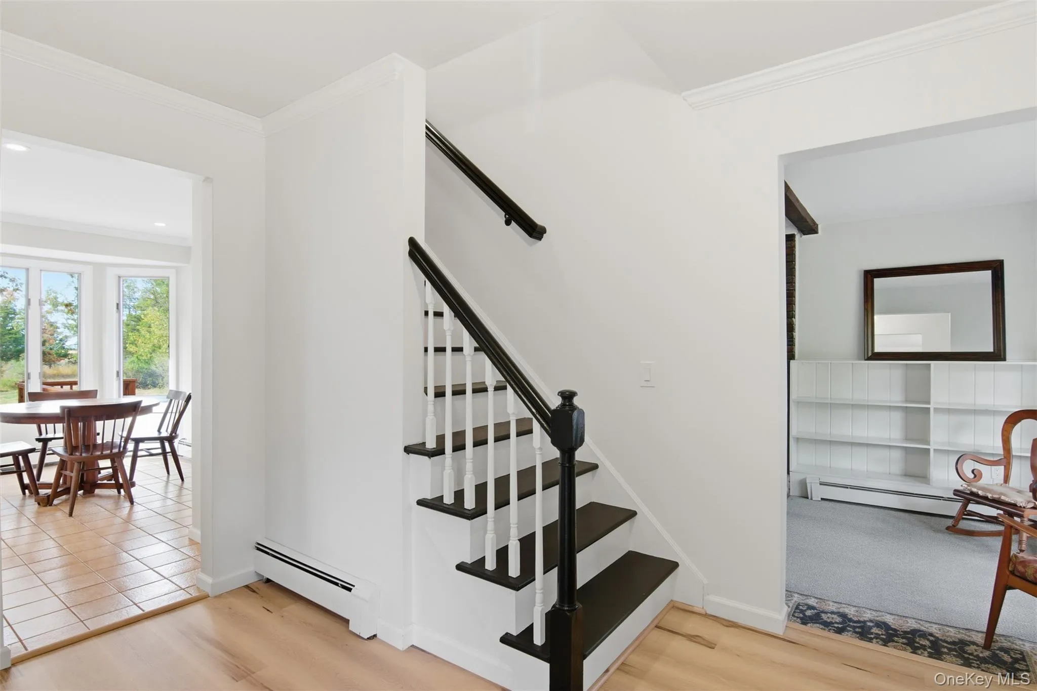 Staircase with ornamental molding, a baseboard heating unit, and wood finished floors Staircase with ornamental molding, a baseboard heating unit, and wood finished floors