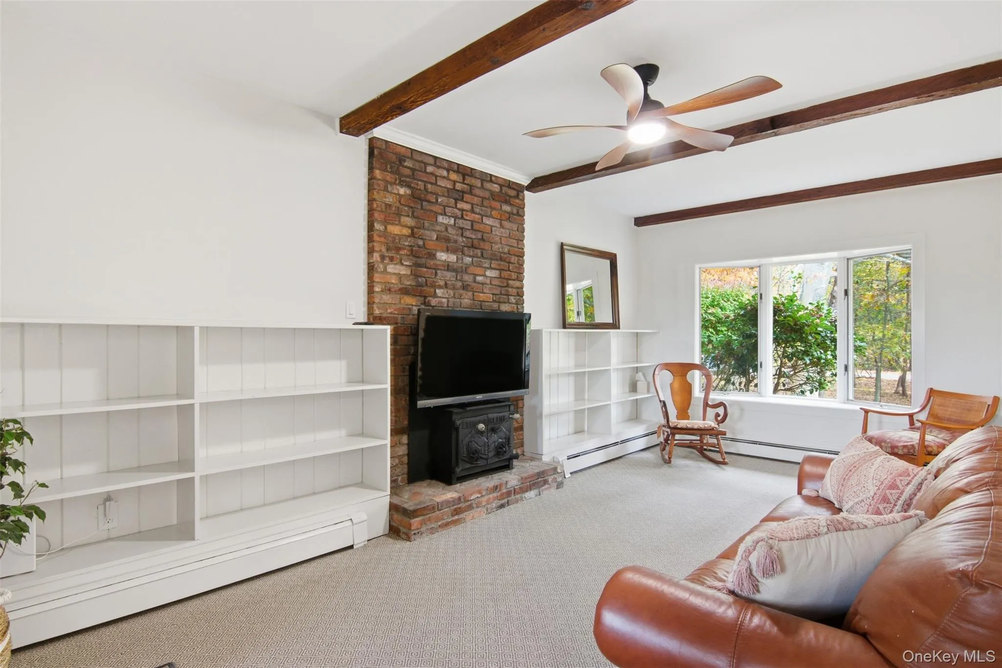 Living room featuring carpet flooring, beam ceiling, ceiling fan, and a baseboard radiator Living room featuring carpet flooring, beam ceiling, ceiling fan, and a baseboard radiator