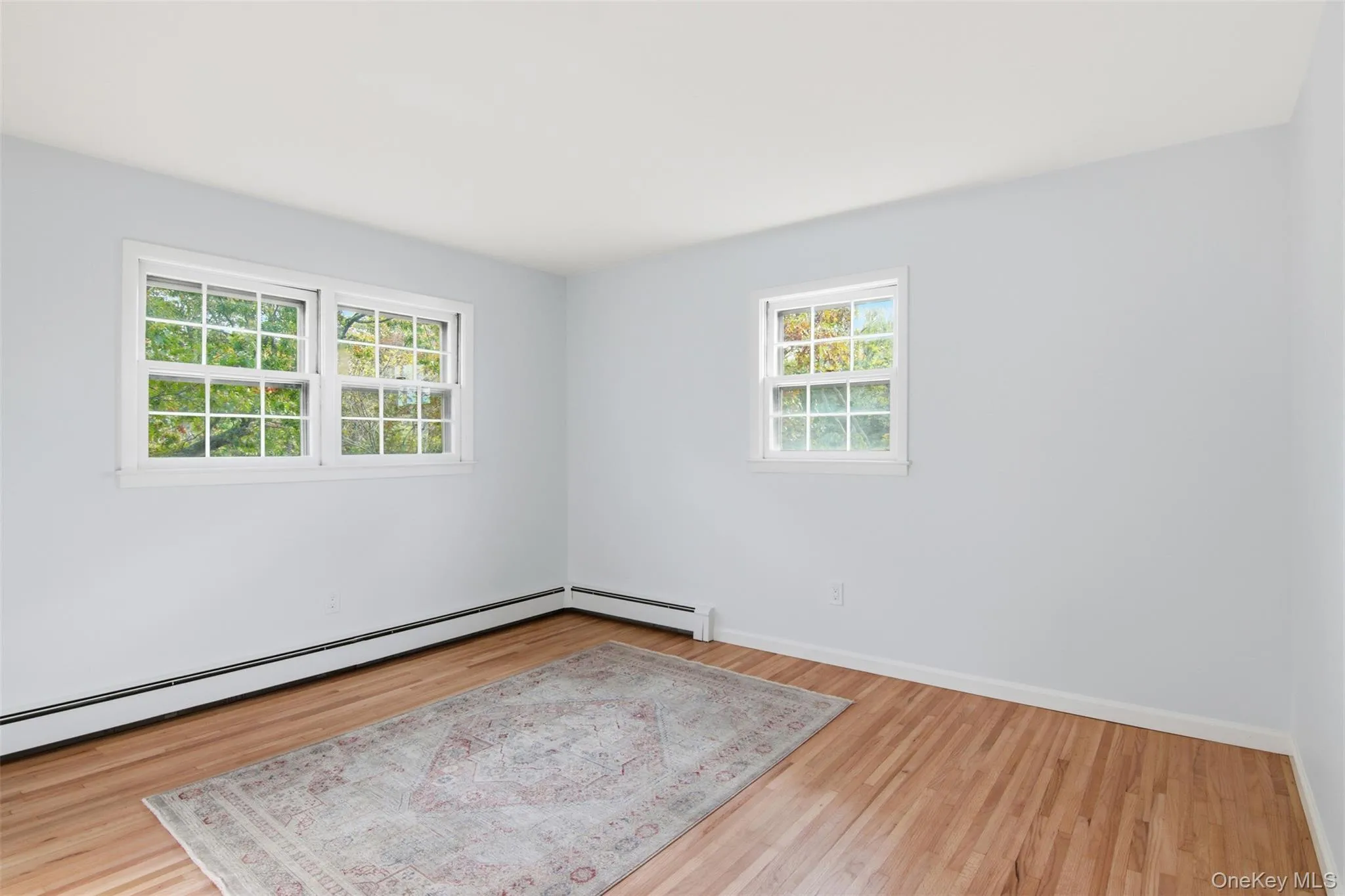 Empty room with light wood-type flooring and baseboard heating Empty room with light wood-type flooring and baseboard heating