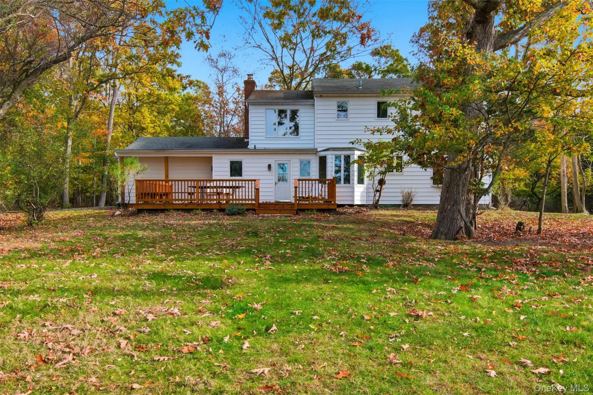 Back of property with a lawn, a chimney, and a deck Back of property with a lawn, a chimney, and a deck