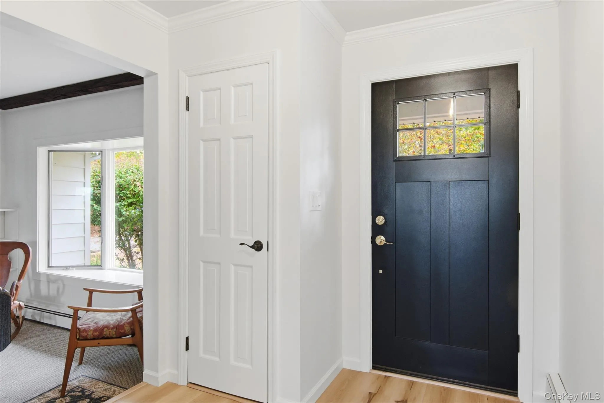 Foyer featuring light wood-style flooring, a baseboard heating unit, and crown molding Foyer featuring light wood-style flooring, a baseboard heating unit, and crown molding