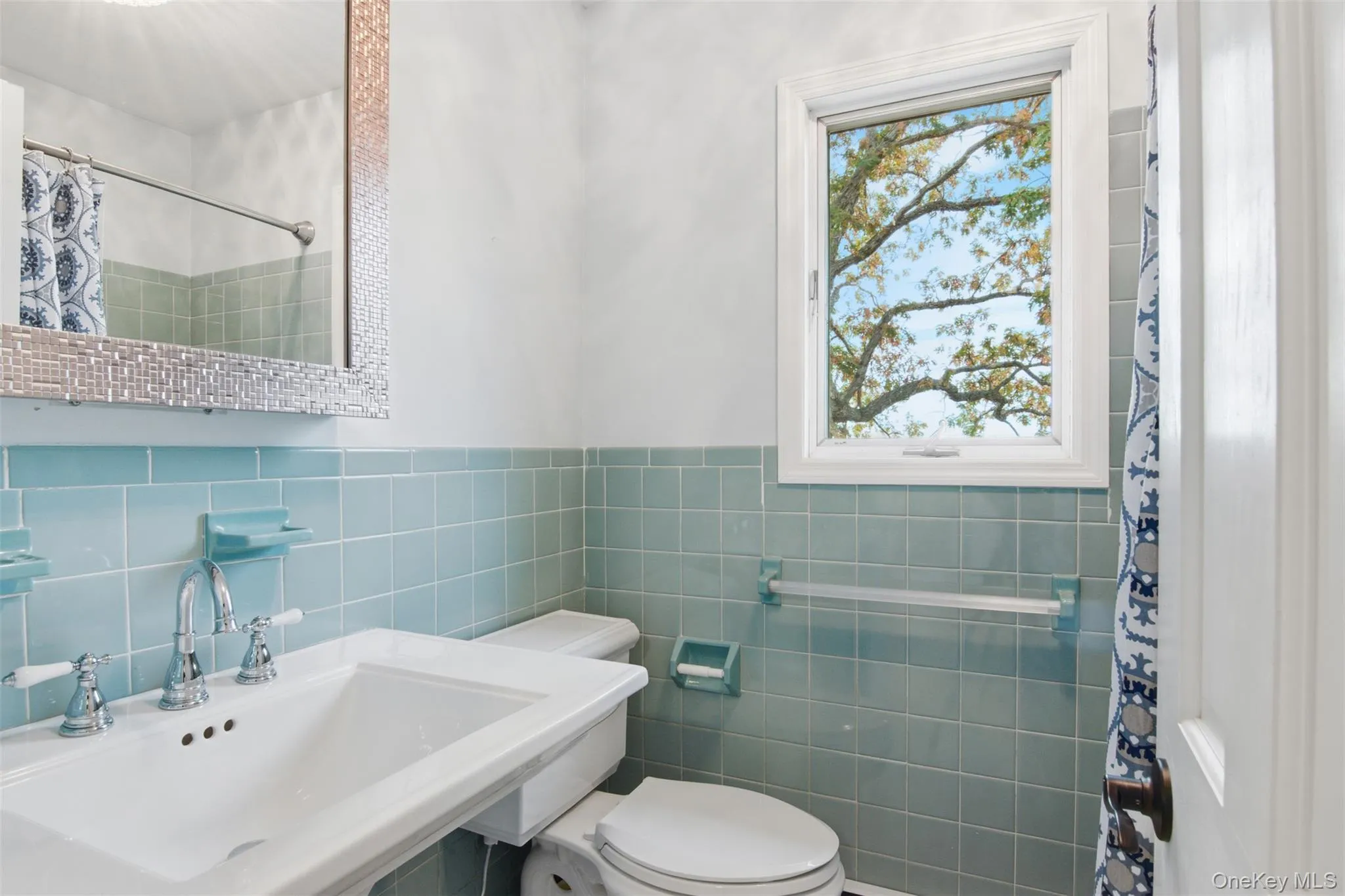 Full bath featuring curtained shower, tile walls, and wainscoting Full bath featuring curtained shower, tile walls, and wainscoting