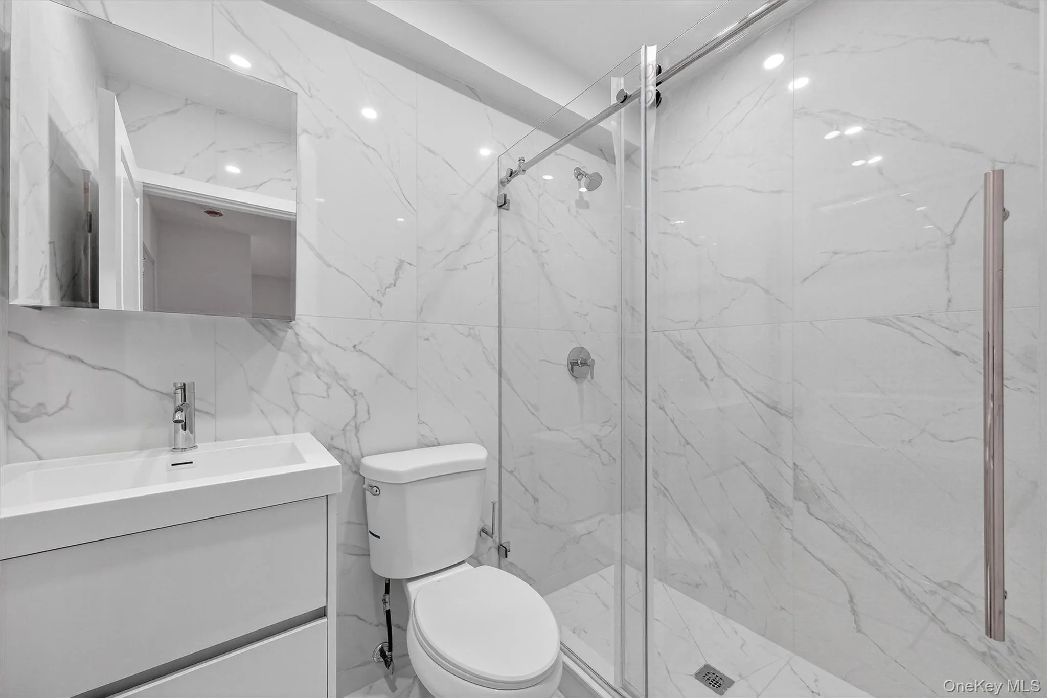 Full bathroom with vanity, tile walls, a marble finish shower, and stone wall Full bathroom with vanity, tile walls, a marble finish shower, and stone wall
