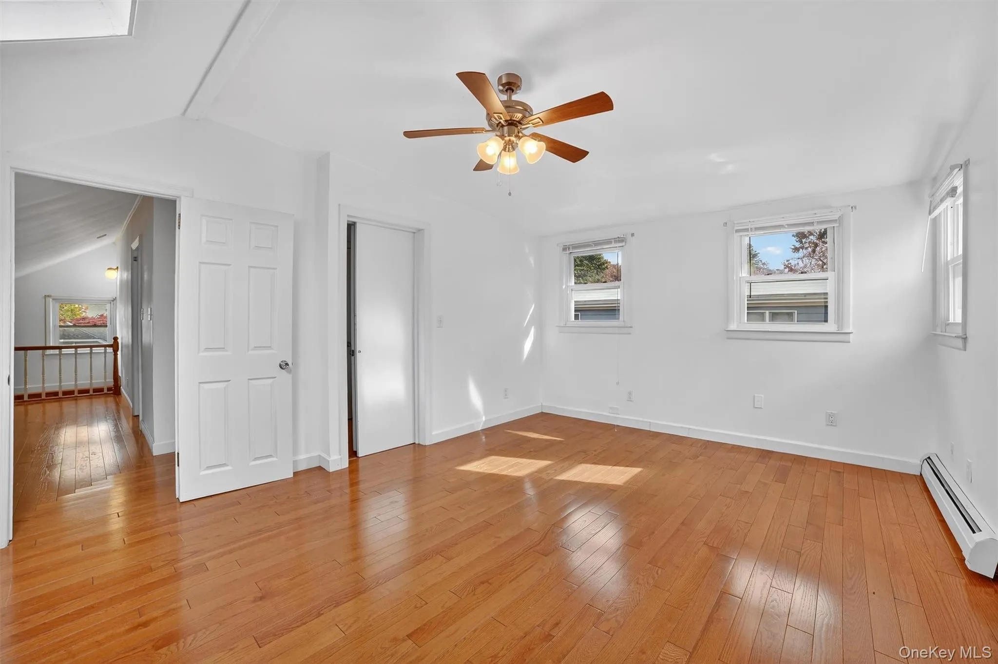Unfurnished bedroom with light wood-style flooring, a baseboard heating unit, ceiling fan, and vaulted ceiling Unfurnished bedroom with light wood-style flooring, a baseboard heating unit, ceiling fan, and vaulted ceiling