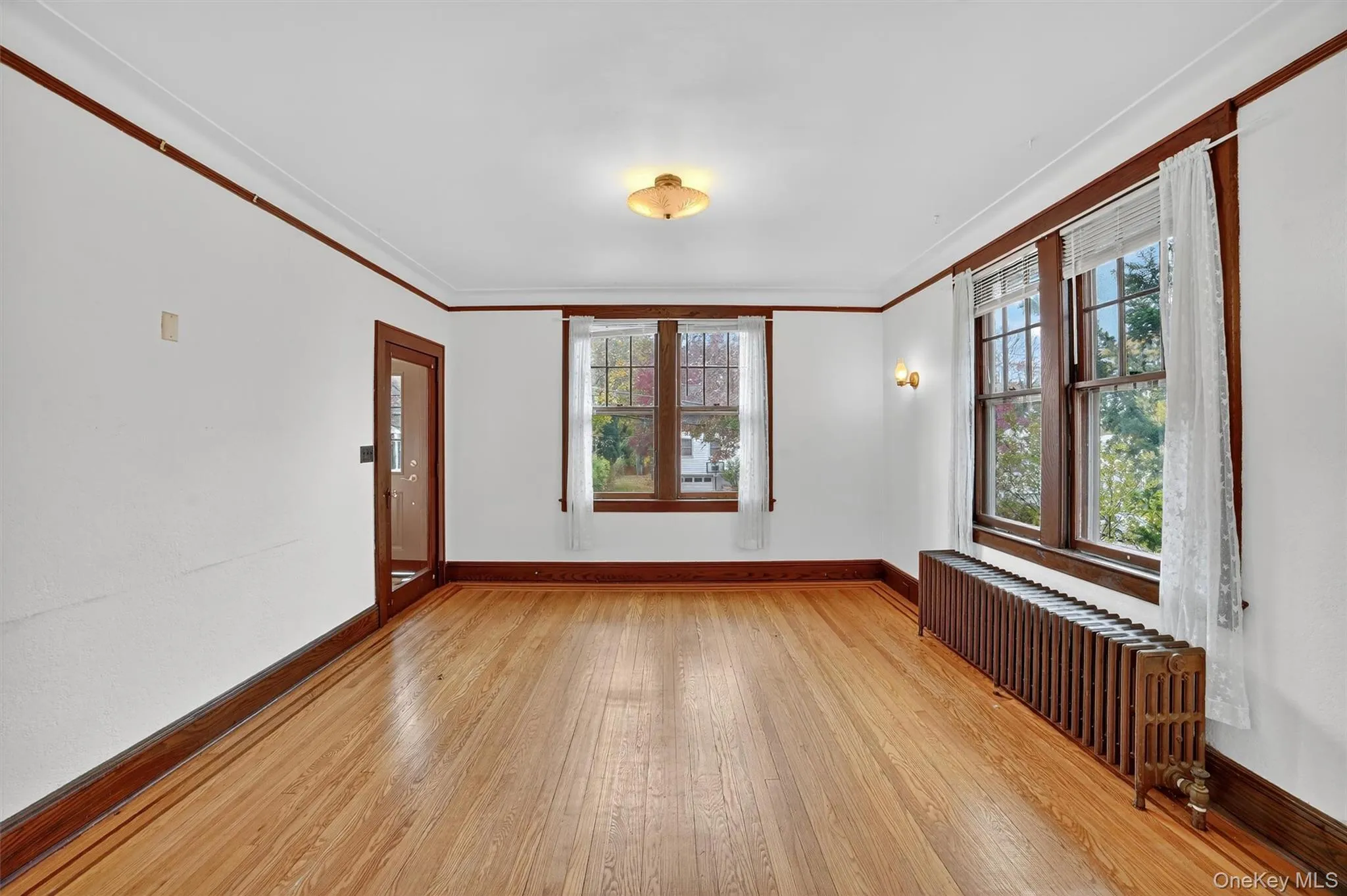 Unfurnished room with radiator heating unit, crown molding, healthy amount of natural light, and light wood-type flooring Unfurnished room with radiator heating unit, crown molding, healthy amount of natural light, and light wood-type flooring