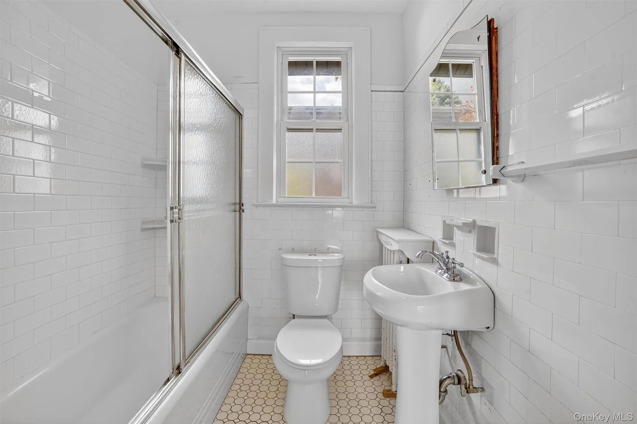 Full bath with enclosed tub / shower combo, tile walls, and light tile patterned floors Full bath with enclosed tub / shower combo, tile walls, and light tile patterned floors