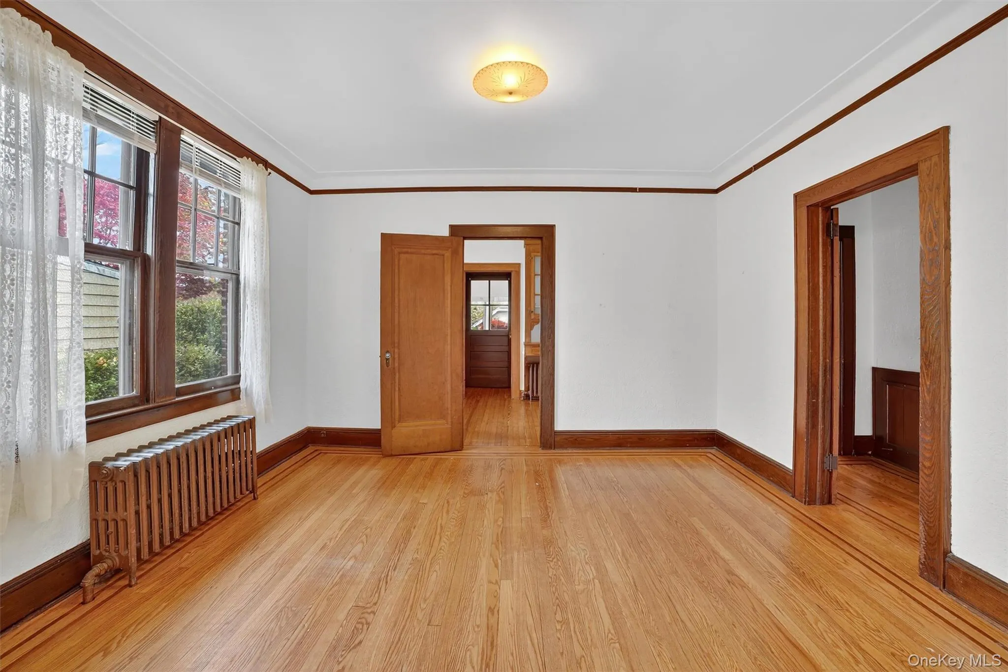 Empty room with ornamental molding, light wood finished floors, and radiator Empty room with ornamental molding, light wood finished floors, and radiator