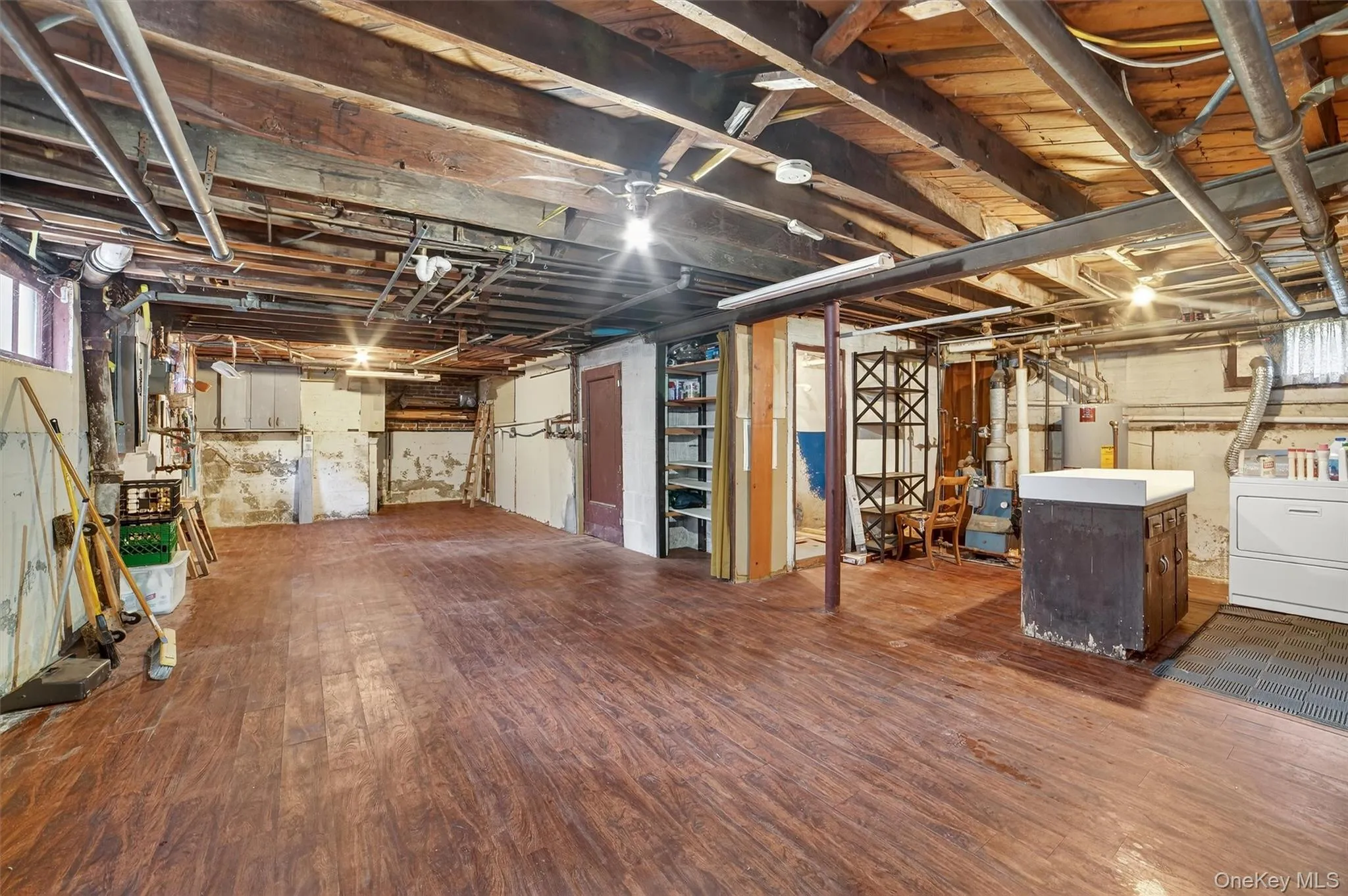 Basement featuring dark wood-style flooring, washer / clothes dryer, and water heater Basement featuring dark wood-style flooring, washer / clothes dryer, and water heater