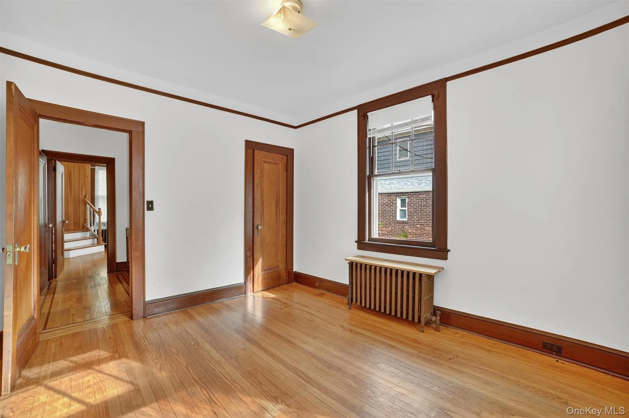 Spare room with light wood-style floors, radiator heating unit, and crown molding Spare room with light wood-style floors, radiator heating unit, and crown molding