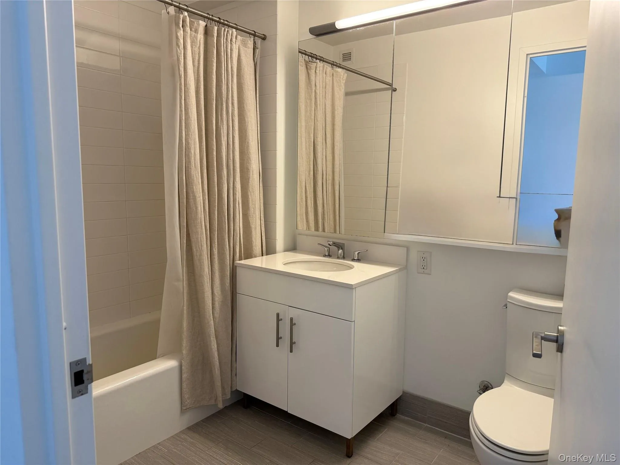 Bathroom featuring shower / bathtub combination with curtain, vanity, and wood finish floors Bathroom featuring shower / bathtub combination with curtain, vanity, and wood finish floors