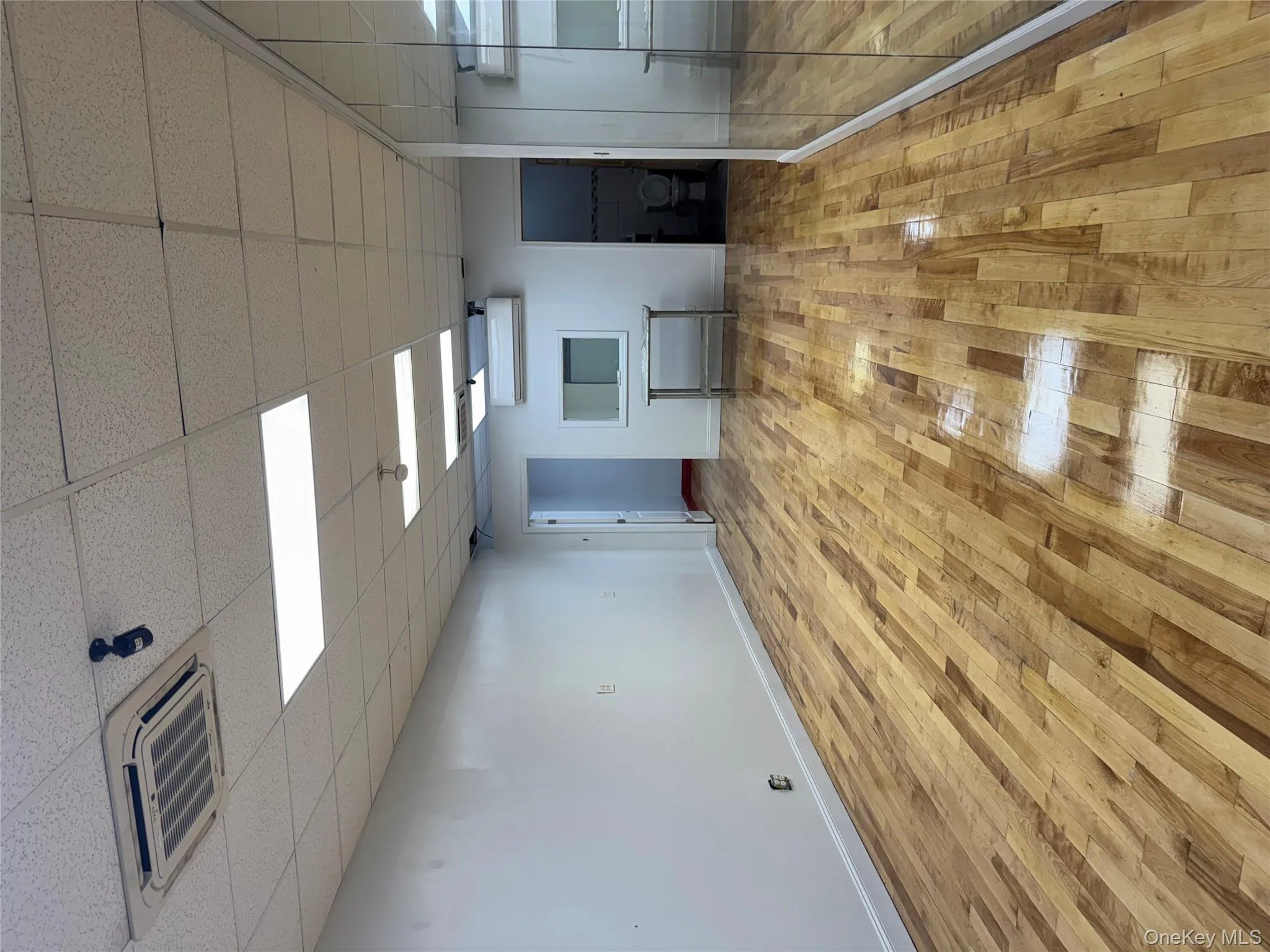 Unfurnished room featuring light wood-type flooring, a paneled ceiling, and a wall unit AC Unfurnished room featuring light wood-type flooring, a paneled ceiling, and a wall unit AC