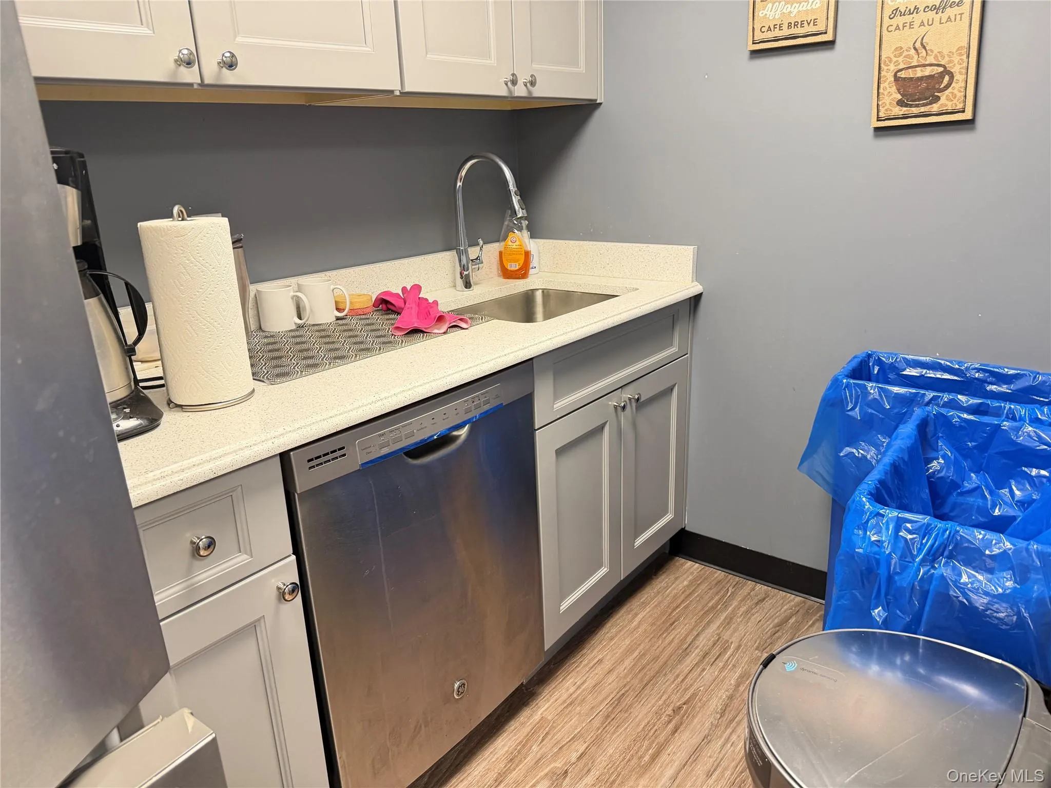 Kitchen featuring appliances with stainless steel finishes, light wood-type flooring, gray cabinets, and light stone counters Kitchen featuring appliances with stainless steel finishes, light wood-type flooring, gray cabinets, and light stone counters
