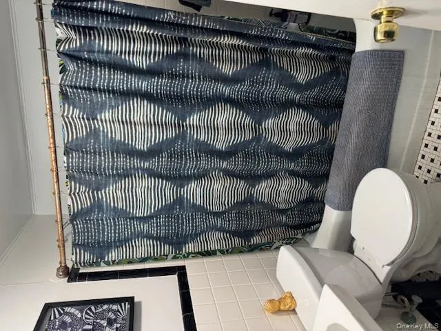 Bathroom with tile walls, shower / bath combination with curtain, tile patterned floors, and crown molding Bathroom with tile walls, shower / bath combination with curtain, tile patterned floors, and crown molding