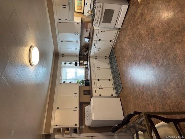 Kitchen featuring dark countertops, stove, washer / clothes dryer, white cabinetry, and ornamental molding Kitchen featuring dark countertops, stove, washer / clothes dryer, white cabinetry, and ornamental molding