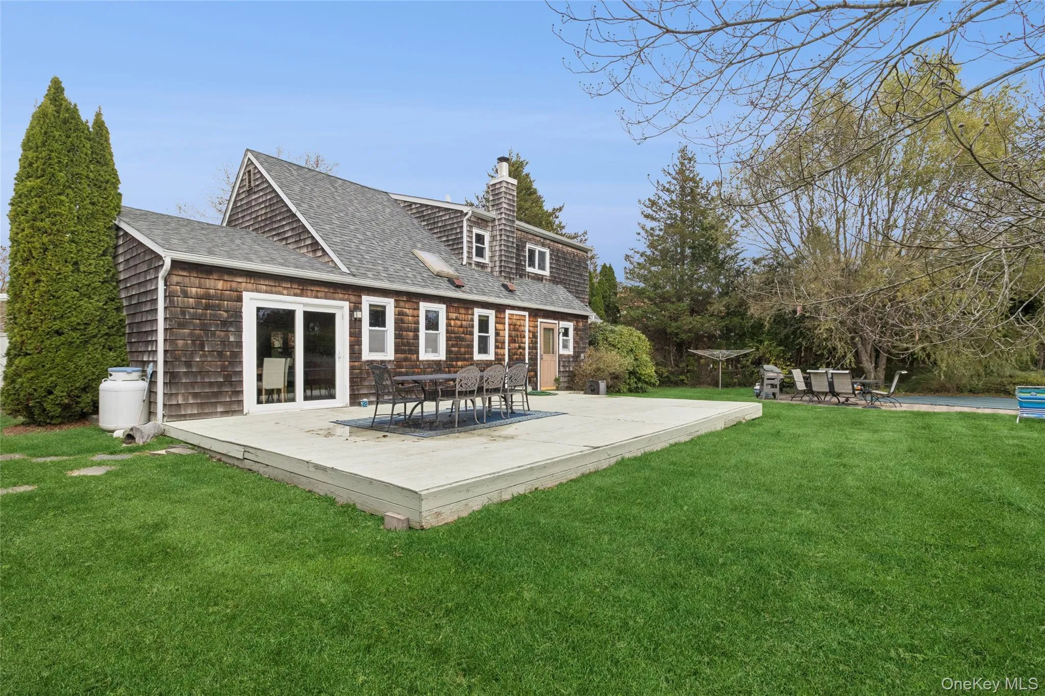 Back of house featuring roof with shingles, a yard, a chimney, and a wooden deck Back of house featuring roof with shingles, a yard, a chimney, and a wooden deck