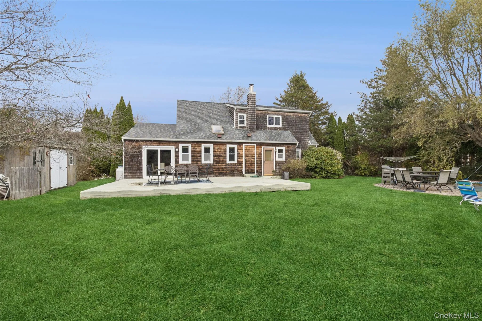 Back of house featuring a patio area, a lawn, a chimney, and roof with shingles Back of house featuring a patio area, a lawn, a chimney, and roof with shingles