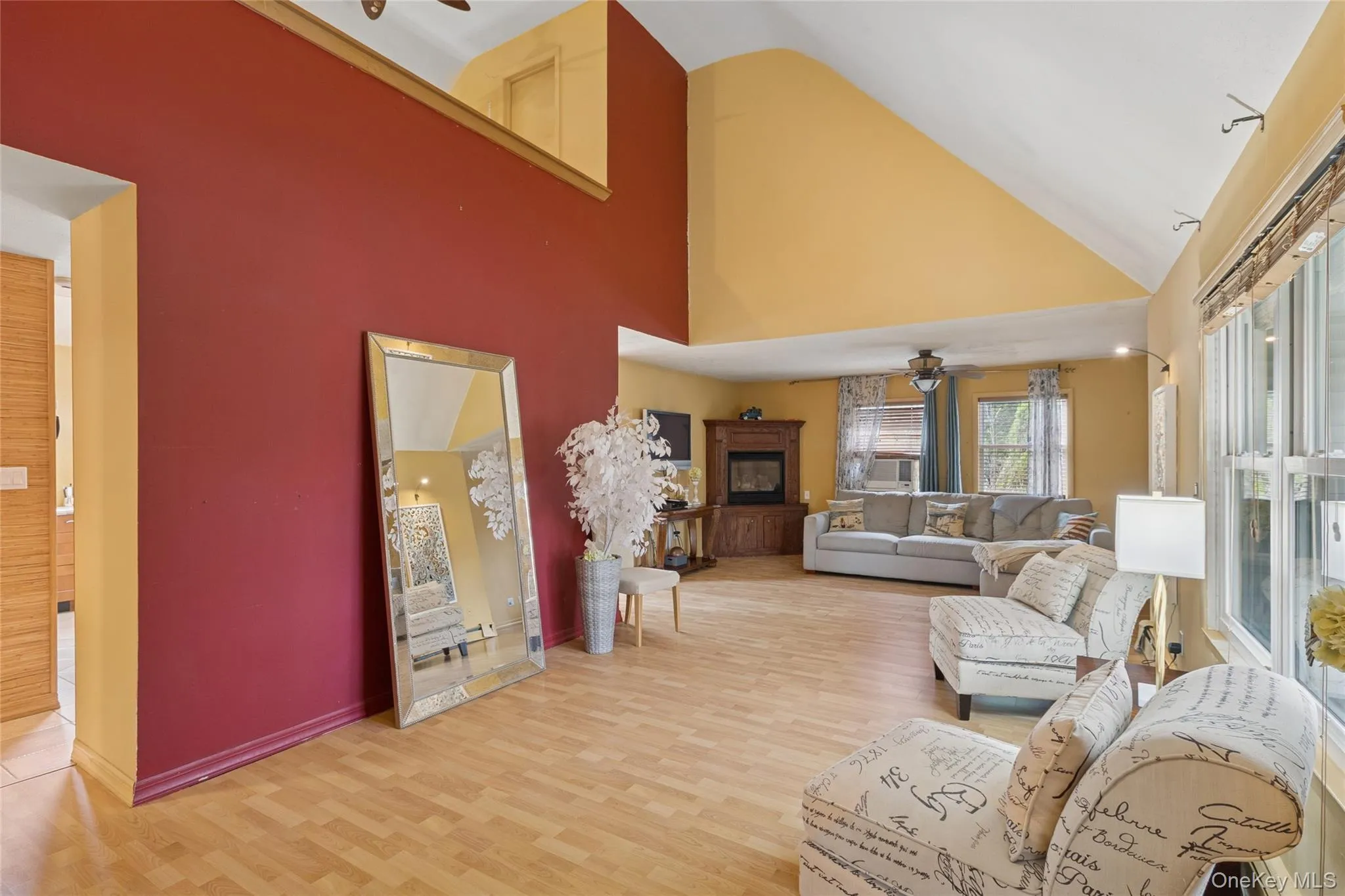 Living room featuring ceiling fan, high vaulted ceiling, and light wood-type flooring Living room featuring ceiling fan, high vaulted ceiling, and light wood-type flooring