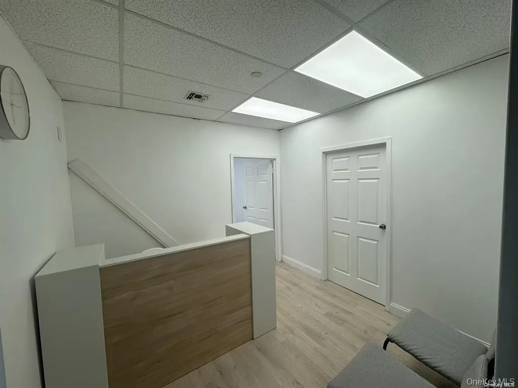 Hall with an upstairs landing, light wood-style floors, and a drop ceiling Hall with an upstairs landing, light wood-style floors, and a drop ceiling