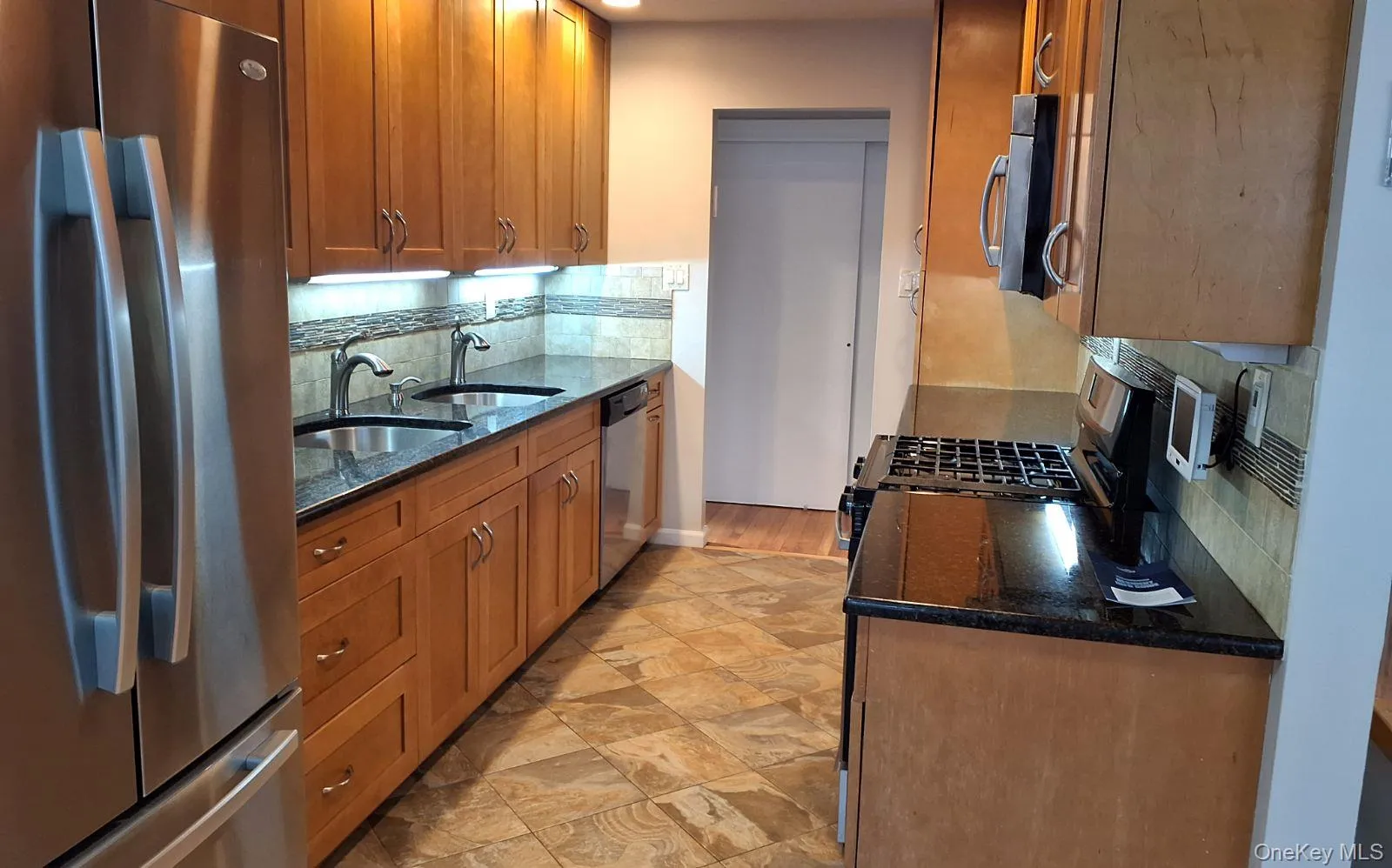 Kitchen featuring stainless steel appliances, dark stone countertops, and backsplash Kitchen featuring stainless steel appliances, dark stone countertops, and backsplash