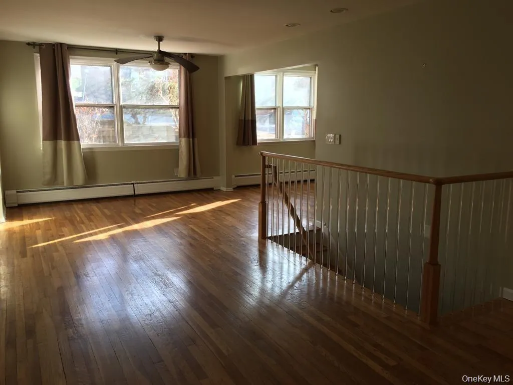 Unfurnished room featuring dark wood-type flooring, baseboard heating, and a ceiling fan Unfurnished room featuring dark wood-type flooring, baseboard heating, and a ceiling fan