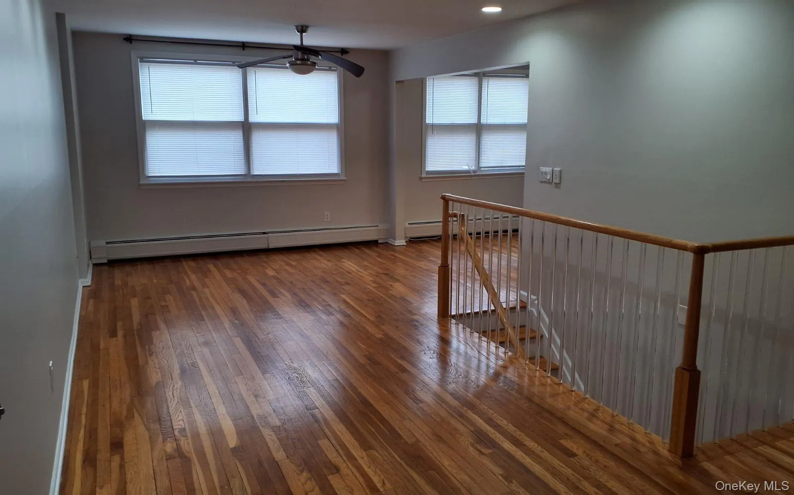 Unfurnished room featuring plenty of natural light, baseboard heating, dark wood-type flooring, and ceiling fan Unfurnished room featuring plenty of natural light, baseboard heating, dark wood-type flooring, and ceiling fan