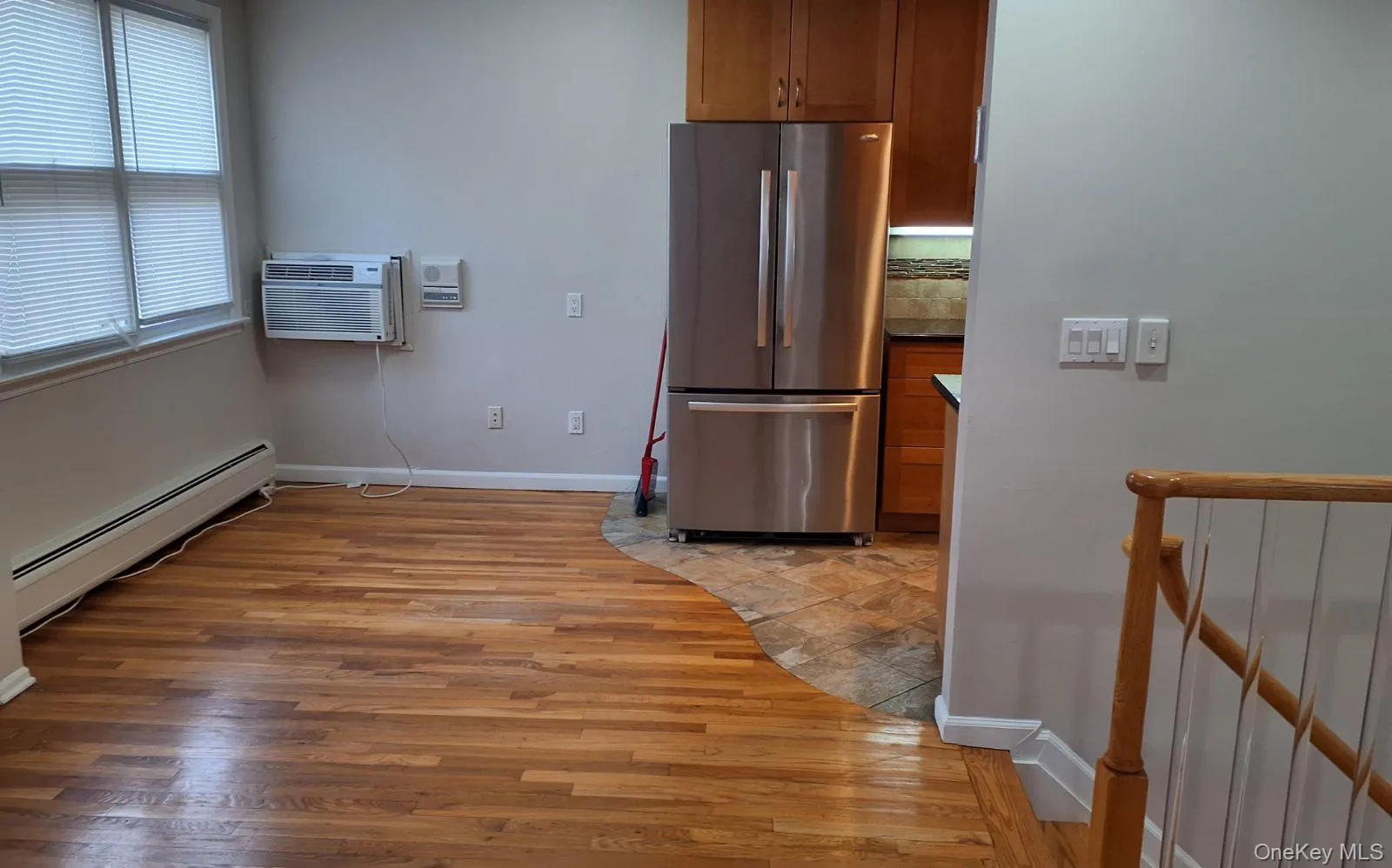 Kitchen featuring brown cabinets, light wood-type flooring, freestanding refrigerator, baseboard heating, and a wall mounted AC Kitchen featuring brown cabinets, light wood-type flooring, freestanding refrigerator, baseboard heating, and a wall mounted AC