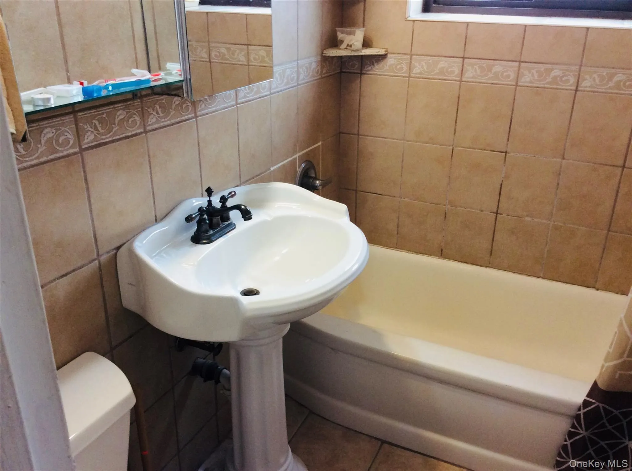 Bathroom featuring a bathtub, tile patterned flooring, and tile walls Bathroom featuring a bathtub, tile patterned flooring, and tile walls