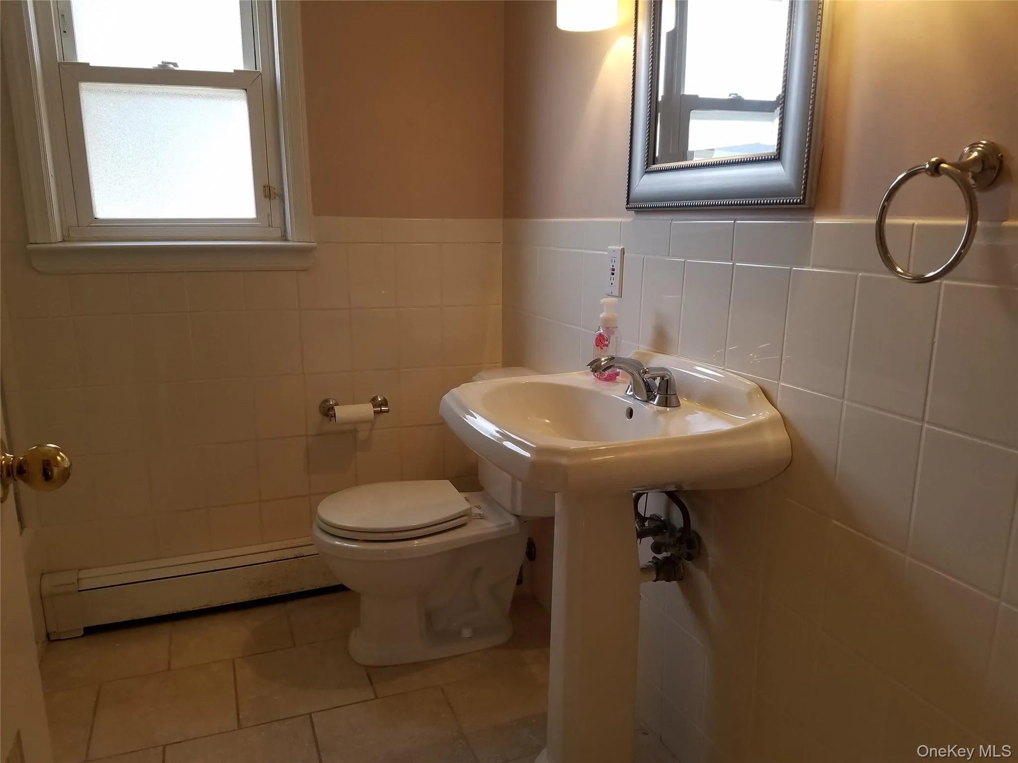 Half bathroom with a baseboard radiator, tile walls, a wainscoted wall, and tile patterned floors Half bathroom with a baseboard radiator, tile walls, a wainscoted wall, and tile patterned floors