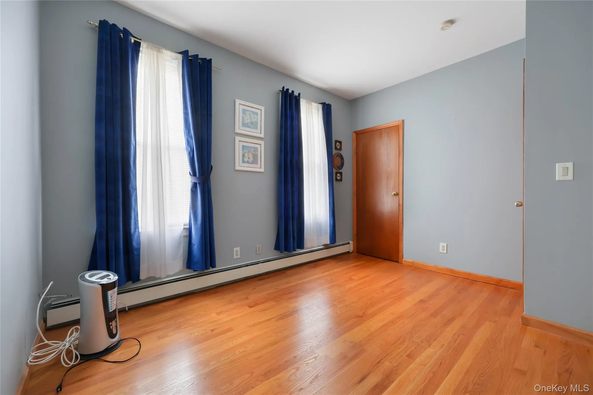 Empty room featuring a baseboard heating unit and light wood-style floors Empty room featuring a baseboard heating unit and light wood-style floors