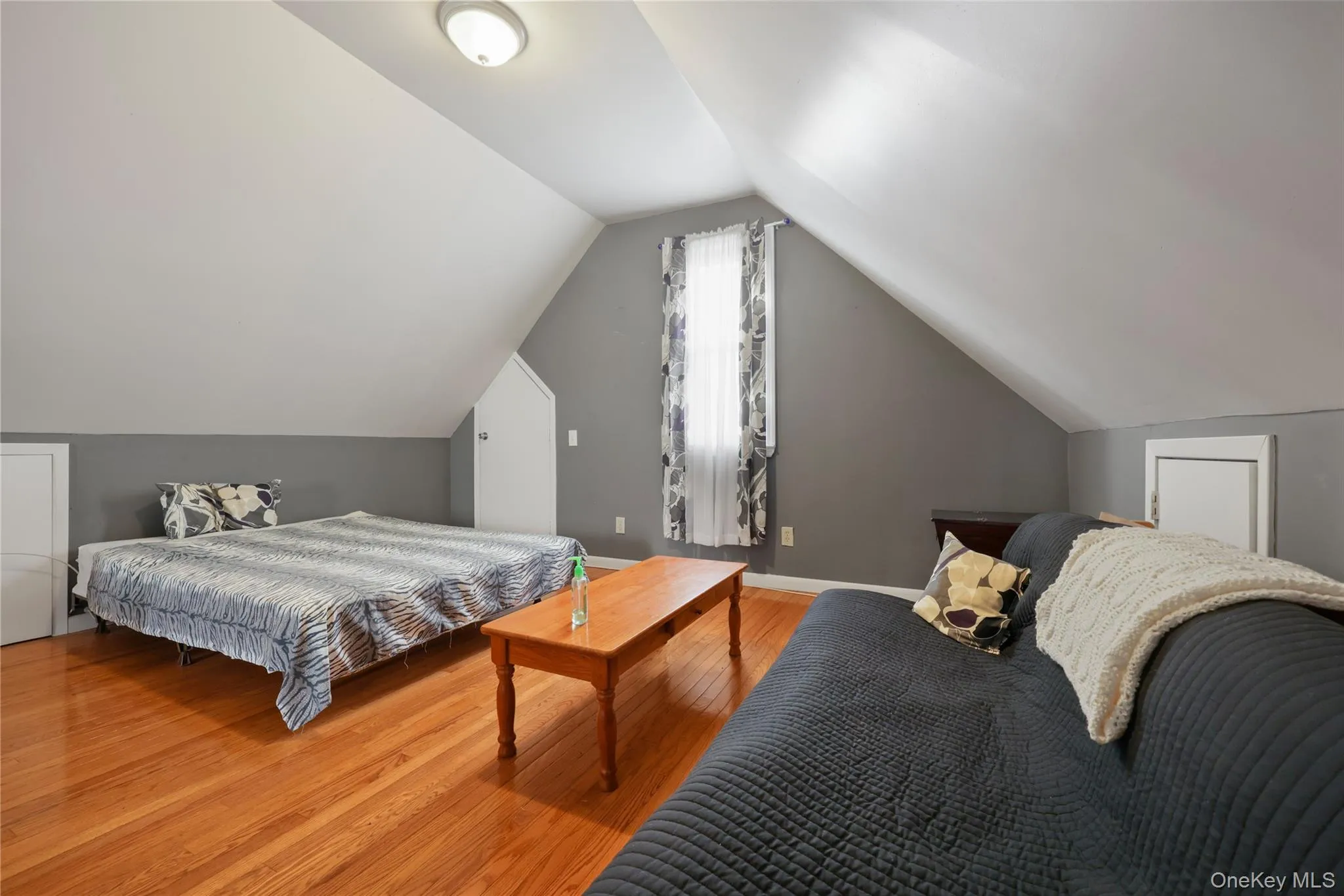 Bedroom featuring lofted ceiling and wood finished floors Bedroom featuring lofted ceiling and wood finished floors