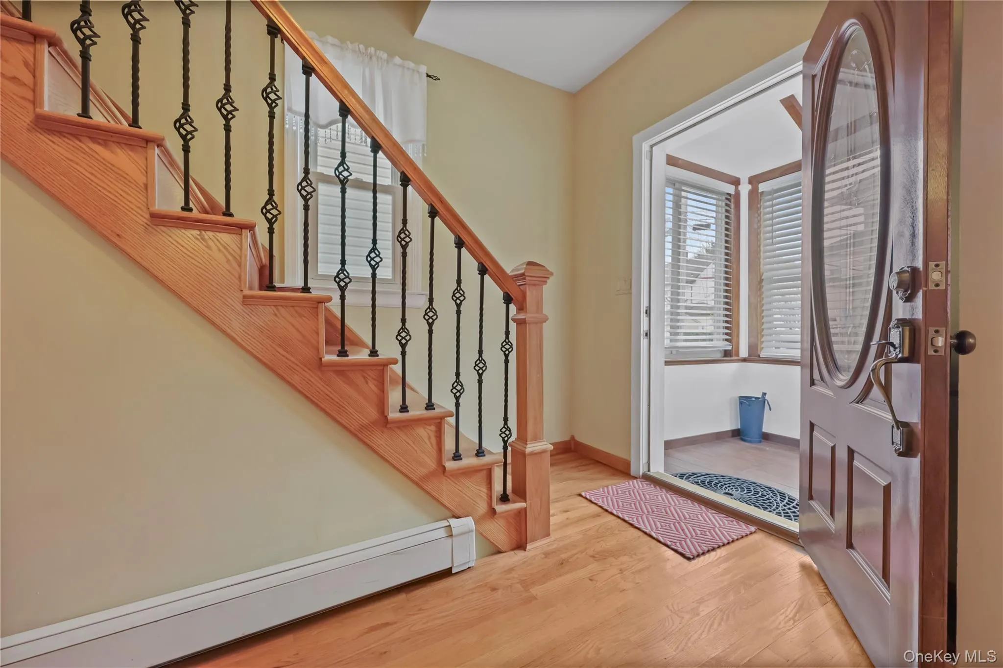 Foyer with baseboard heating, light wood finished floors, and stairs Foyer with baseboard heating, light wood finished floors, and stairs