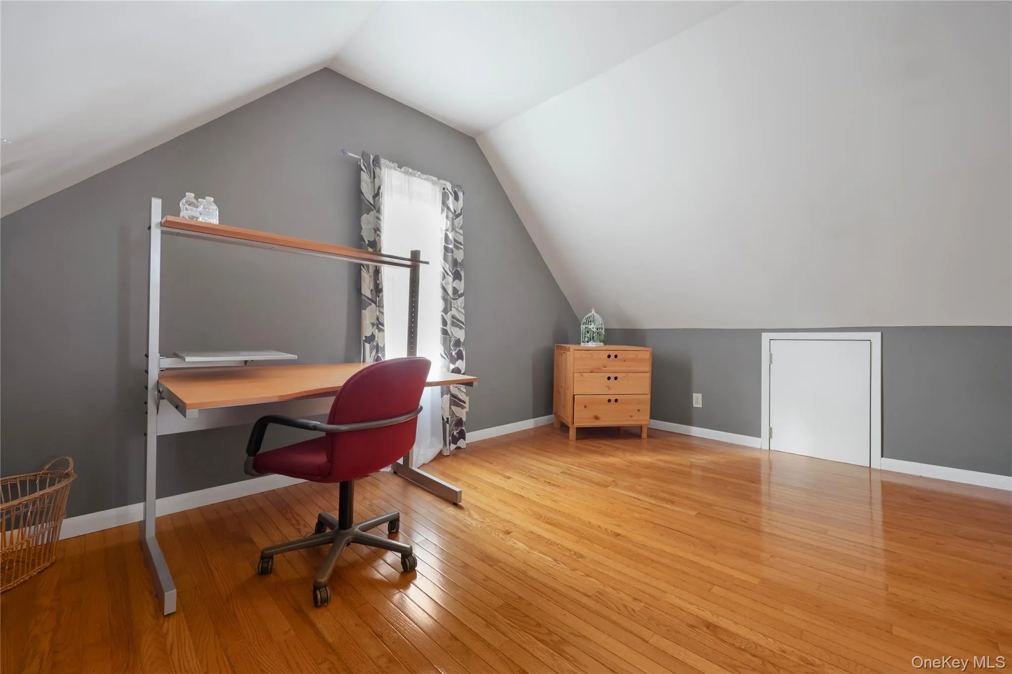 Home office with light wood-type flooring and lofted ceiling Home office with light wood-type flooring and lofted ceiling