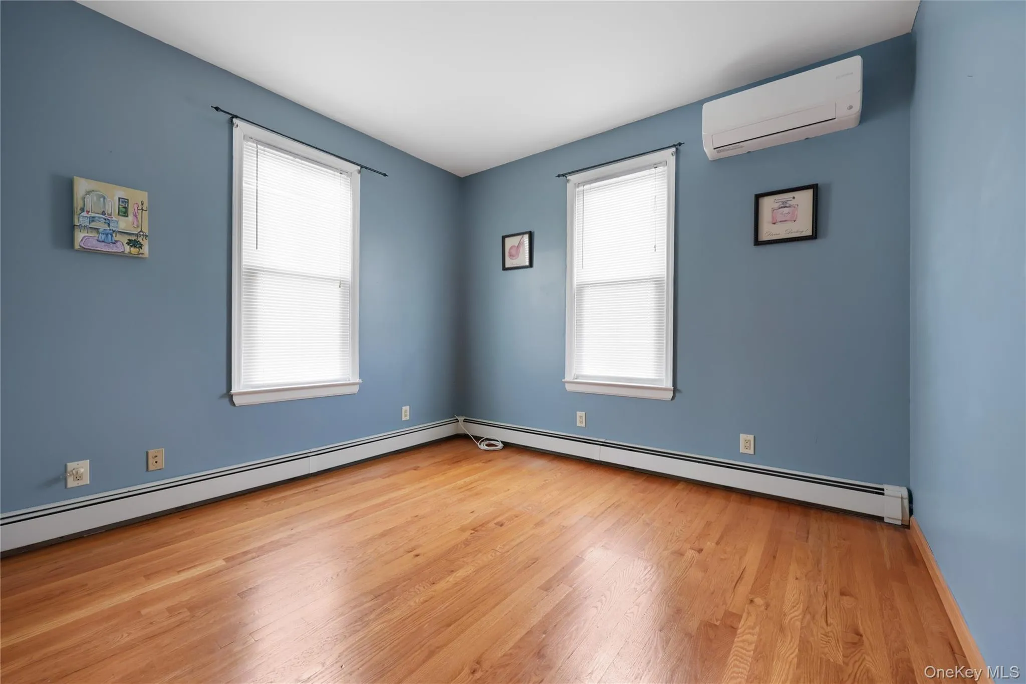 Unfurnished room featuring a baseboard heating unit, light wood-style floors, and a wall mounted AC Unfurnished room featuring a baseboard heating unit, light wood-style floors, and a wall mounted AC