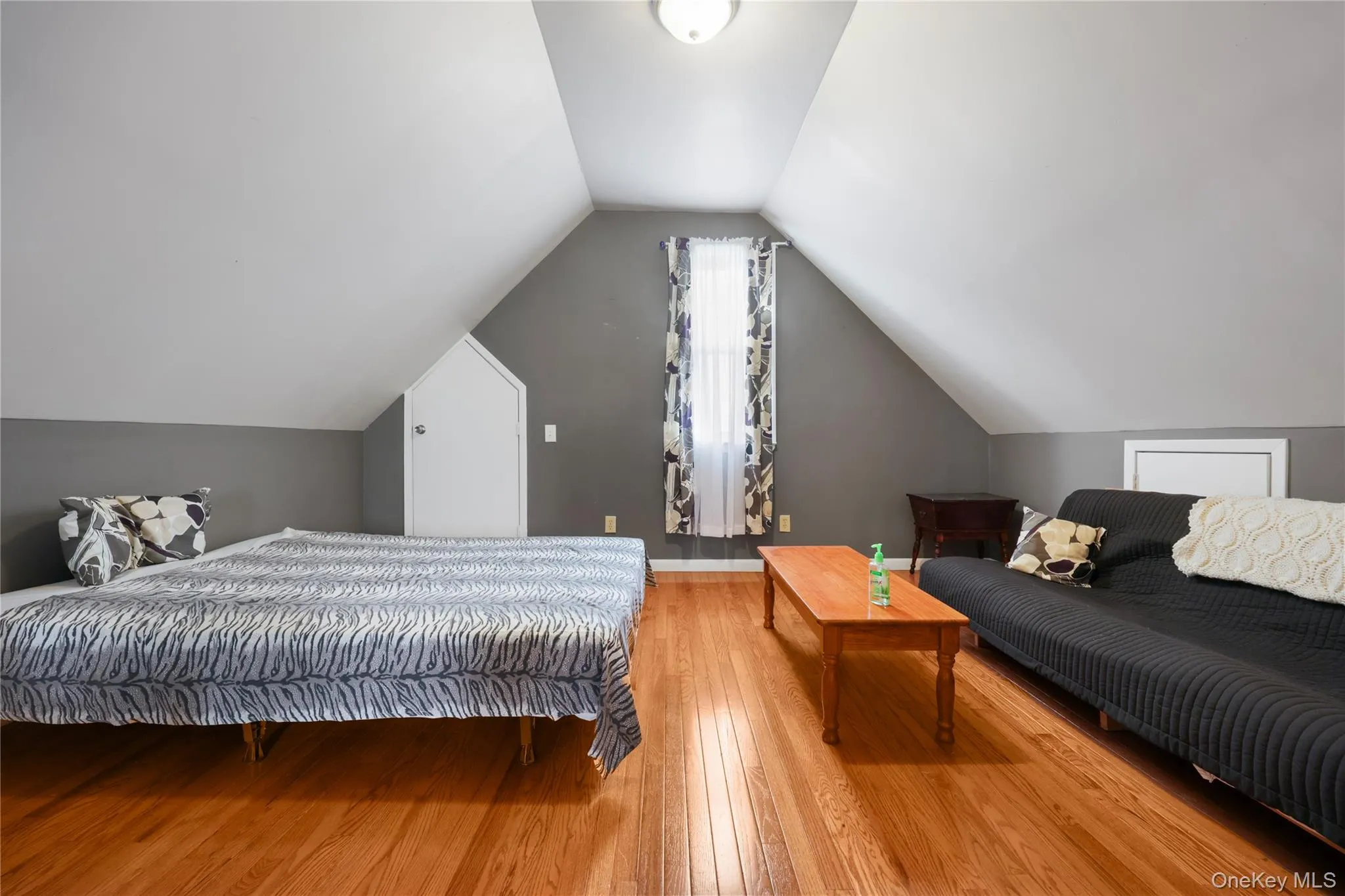 Bedroom with lofted ceiling and hardwood / wood-style floors Bedroom with lofted ceiling and hardwood / wood-style floors