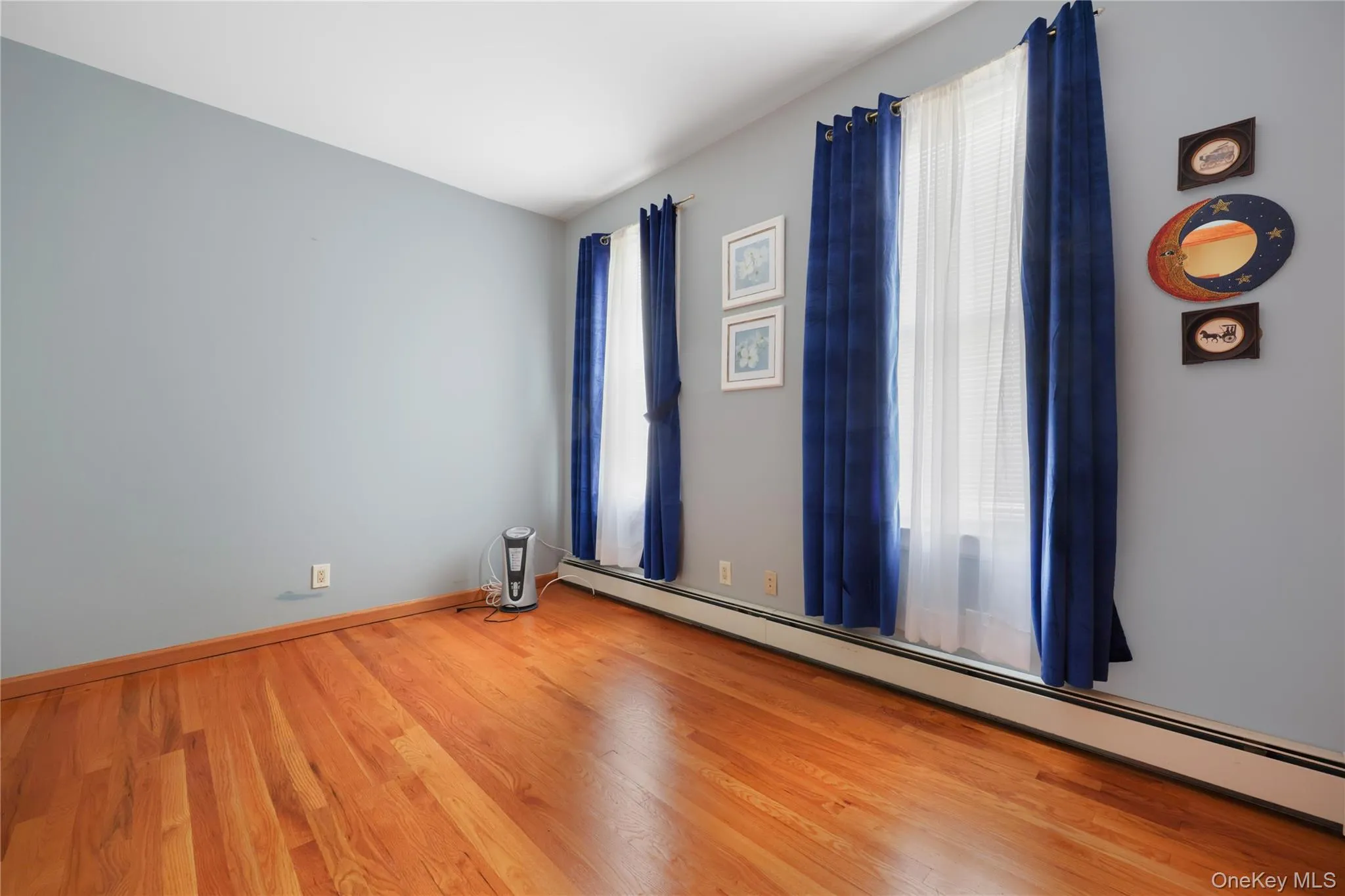Empty room featuring baseboard heating and wood finished floors Empty room featuring baseboard heating and wood finished floors