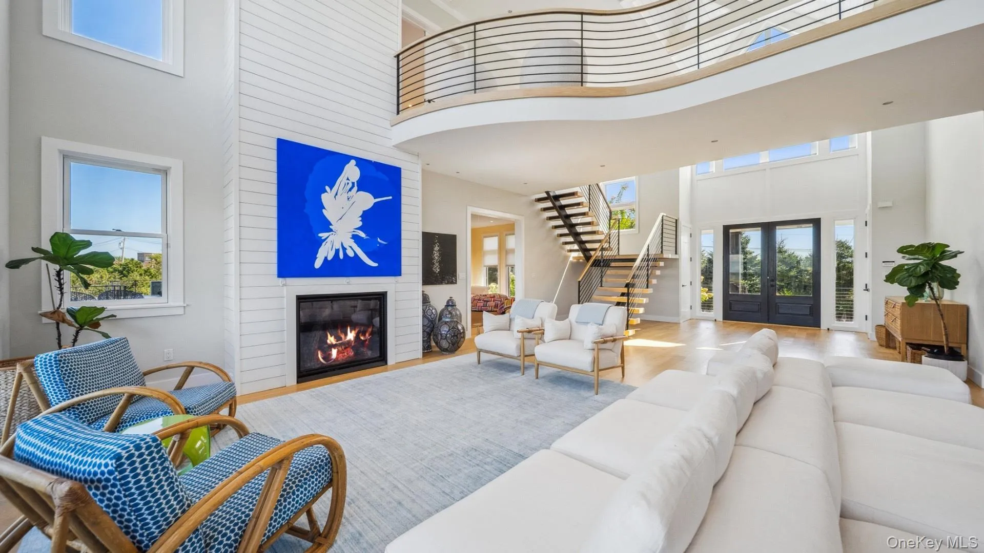 Living room featuring french doors, a high ceiling, stairs, a fireplace, and wood finished floors Living room featuring french doors, a high ceiling, stairs, a fireplace, and wood finished floors