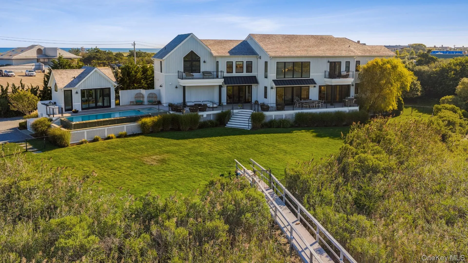 Rear view of house with a fenced backyard, a patio area, a balcony, a standing seam roof, and an outdoor structure Rear view of house with a fenced backyard, a patio area, a balcony, a standing seam roof, and an outdoor structure