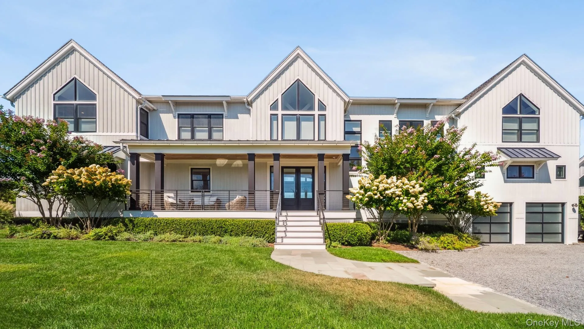 View of front of home with a porch, a front yard, gravel driveway, french doors, and a garage View of front of home with a porch, a front yard, gravel driveway, french doors, and a garage