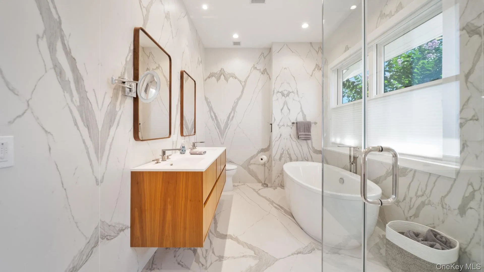 Bathroom featuring stone wall, vanity, a freestanding tub, recessed lighting, and light marble finish floors Bathroom featuring stone wall, vanity, a freestanding tub, recessed lighting, and light marble finish floors