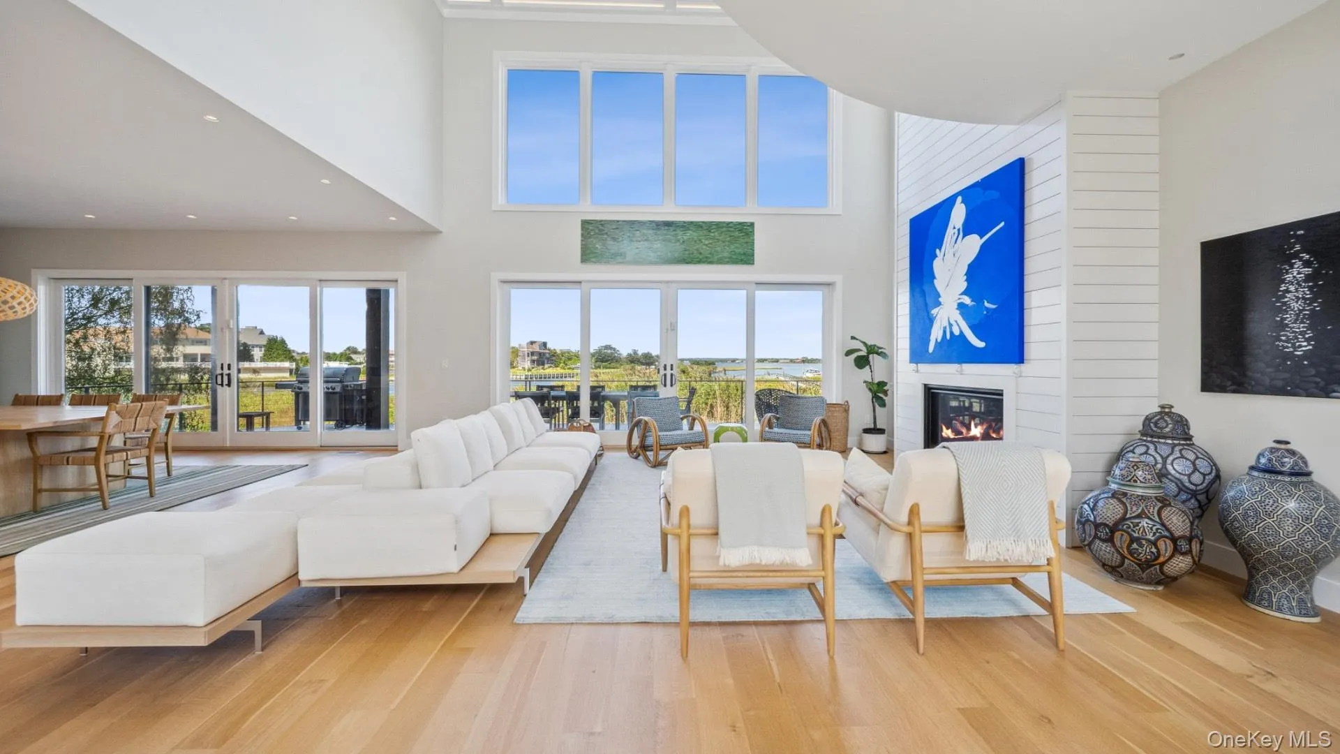 Living area featuring wood finished floors, a high ceiling, french doors, and a large fireplace Living area featuring wood finished floors, a high ceiling, french doors, and a large fireplace