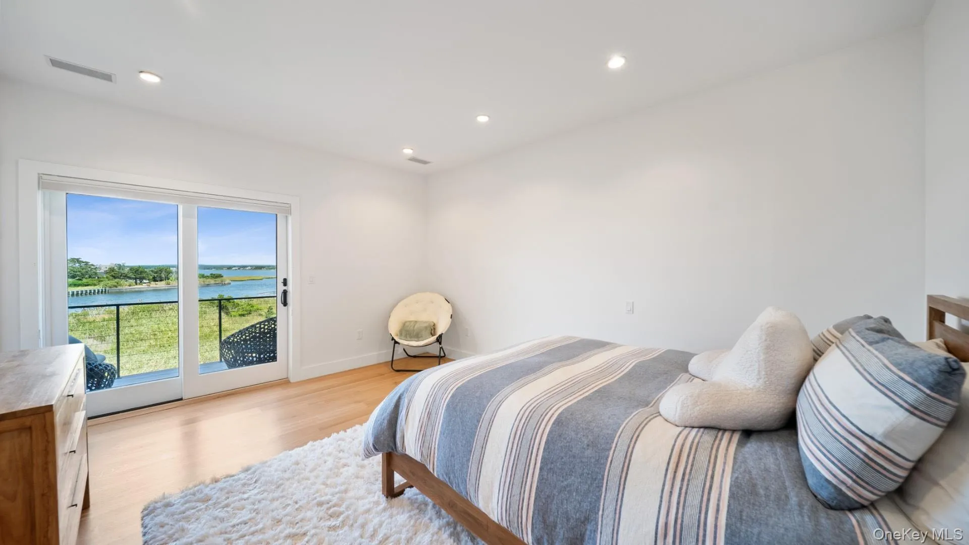 Bedroom featuring a water view, recessed lighting, light wood finished floors, and access to outside Bedroom featuring a water view, recessed lighting, light wood finished floors, and access to outside