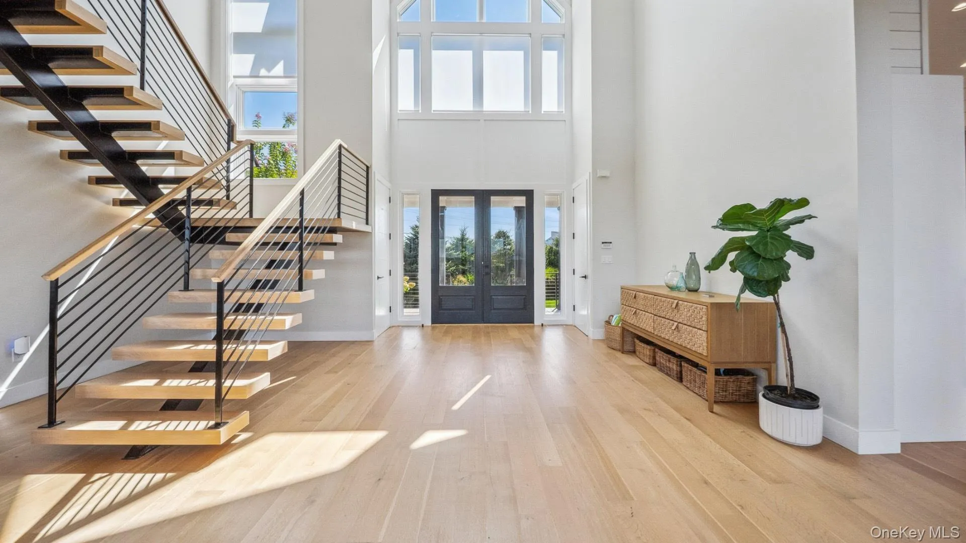 Entryway with french doors, light wood-style floors, stairs, and a high ceiling Entryway with french doors, light wood-style floors, stairs, and a high ceiling