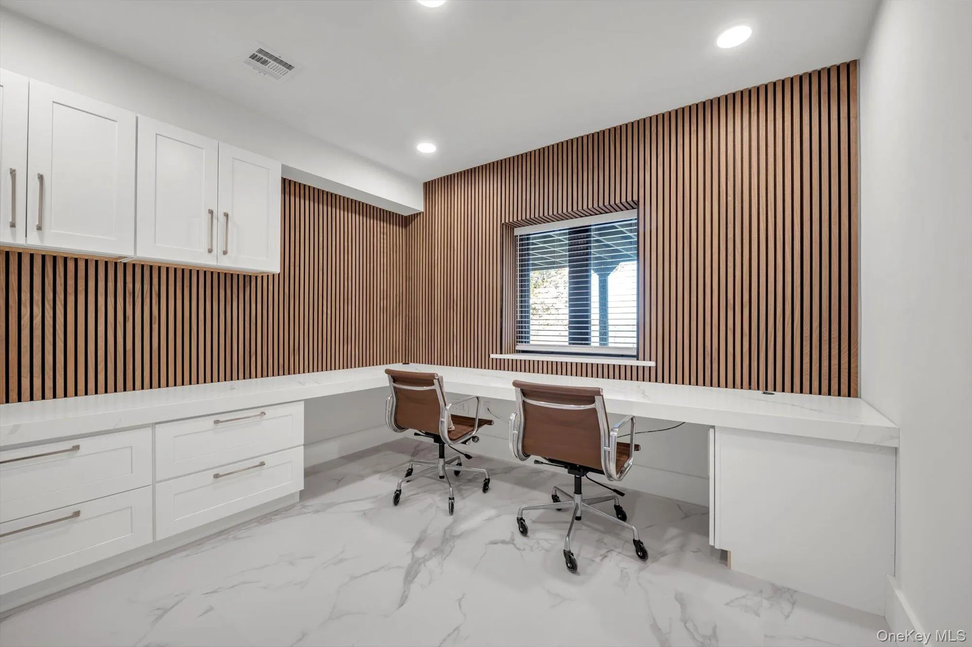 Office area with built in desk, recessed lighting, light marble finish flooring, and wood walls Office area with built in desk, recessed lighting, light marble finish flooring, and wood walls