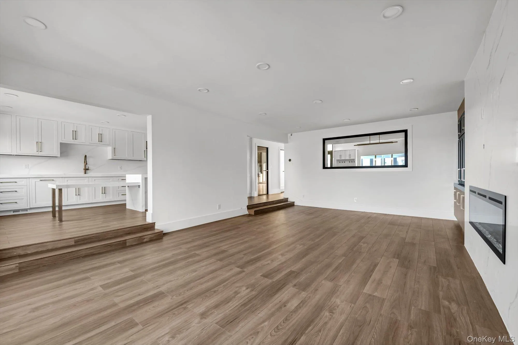 Unfurnished living room featuring recessed lighting and dark wood-style flooring Unfurnished living room featuring recessed lighting and dark wood-style flooring