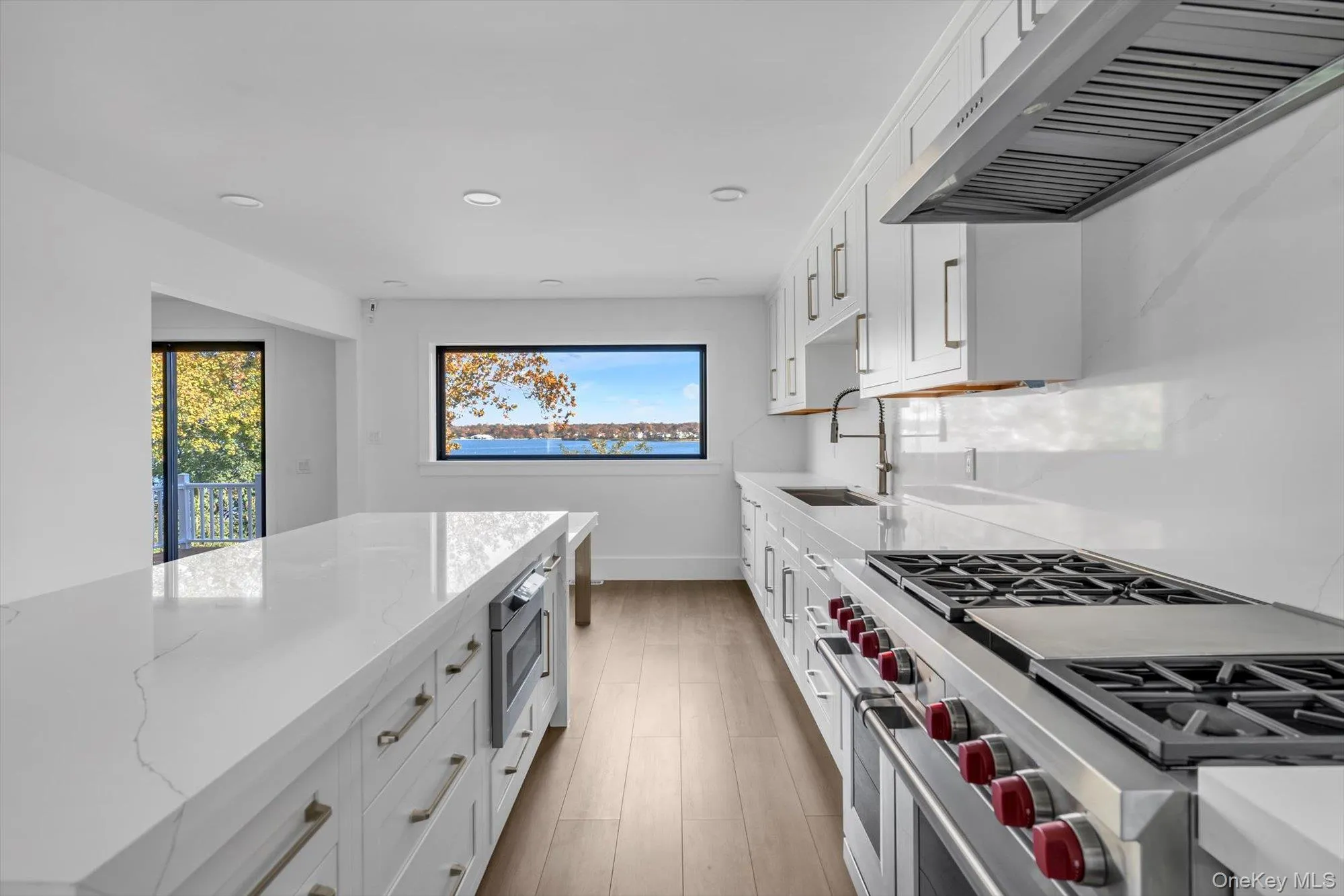Kitchen featuring white cabinetry, range with two ovens, exhaust hood, recessed lighting, and wood finished floors Kitchen featuring white cabinetry, range with two ovens, exhaust hood, recessed lighting, and wood finished floors