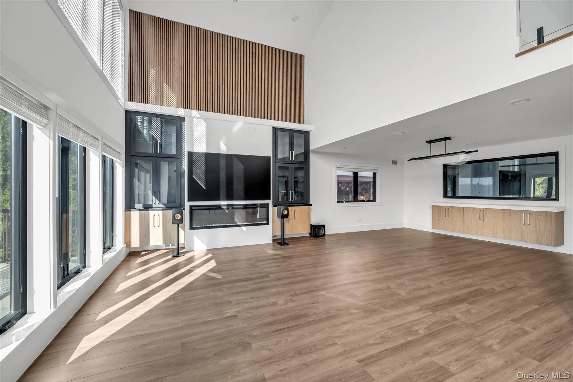 Unfurnished living room with a towering ceiling and light wood-type flooring Unfurnished living room with a towering ceiling and light wood-type flooring