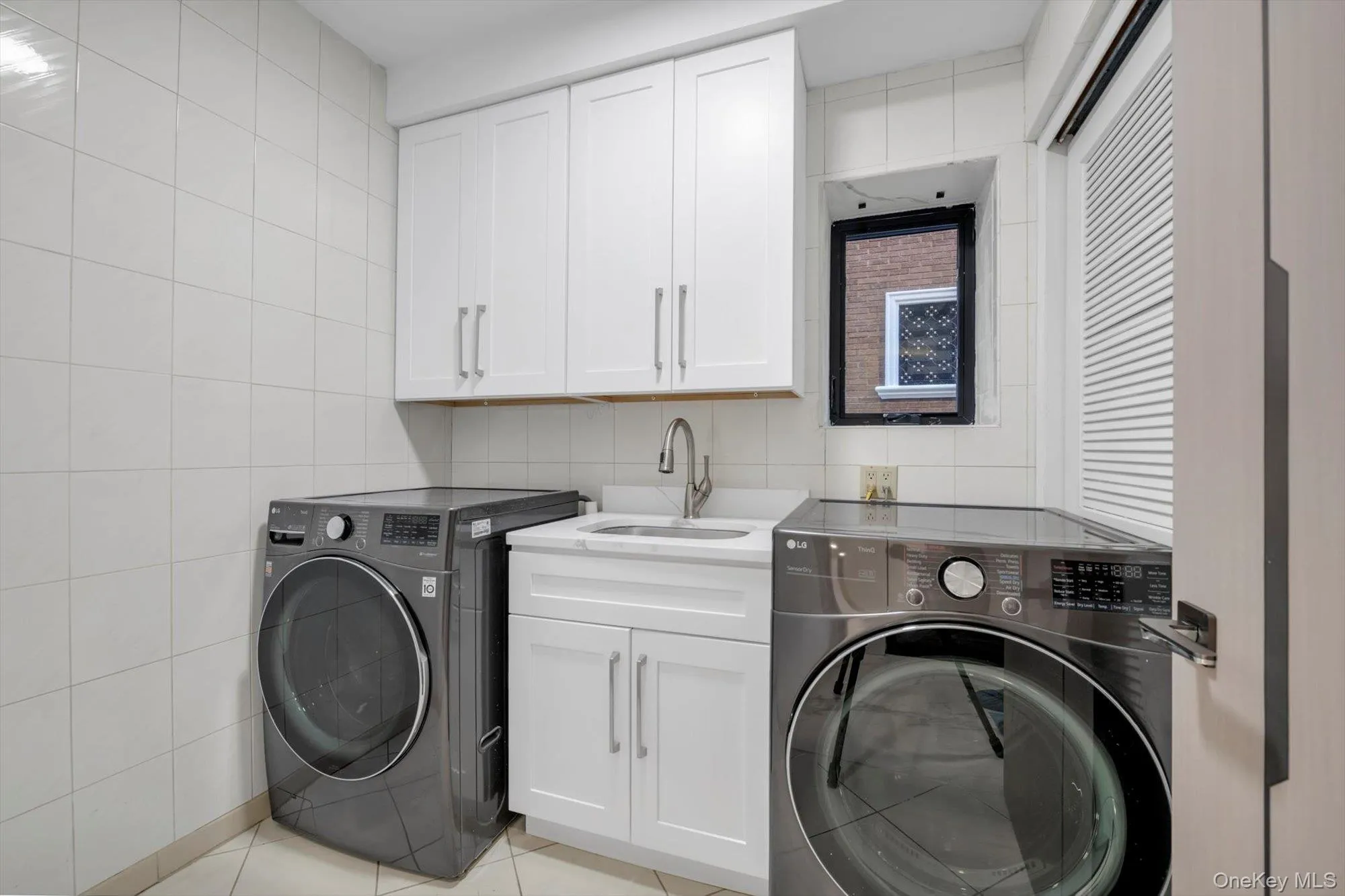 Laundry area featuring tile walls, cabinet space, light tile patterned floors, and washing machine and dryer Laundry area featuring tile walls, cabinet space, light tile patterned floors, and washing machine and dryer